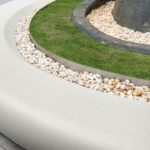 White curve stone bench decorated with white gravel and lawn. fo